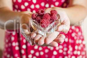 Woman holding a cup of raspberries
