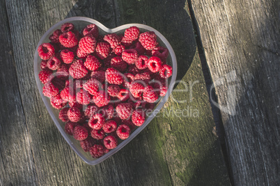 Raspberries in a bowl on wood