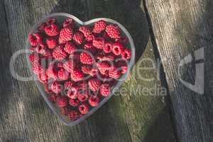 Raspberries in a bowl on wood