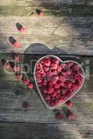 Raspberries in a bowl on wood