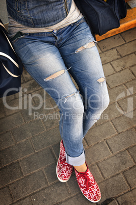 girl in ripped jeans sitting on the bench