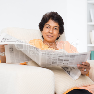 Indian mature woman reading news paper
