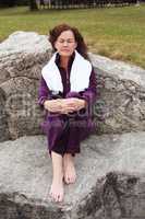 Entspannende Frau sitzt nach der Arbeit auf einen großen Felsen