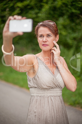 Frau in einem Kleid nimmt ein Selbstporträt mit dem Handy auf