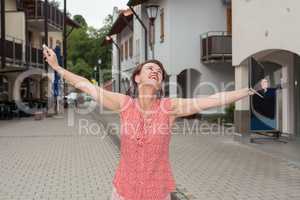 Fröhliche Frau mit offenen Armen auf einer Strasse in der Stadt