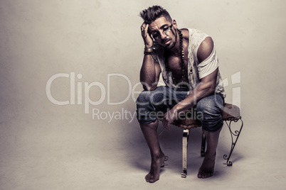 Muscular Man in Ragged Clothes Sitting on a Chair
