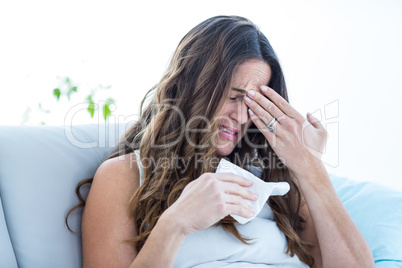 Sick woman crying on sofa