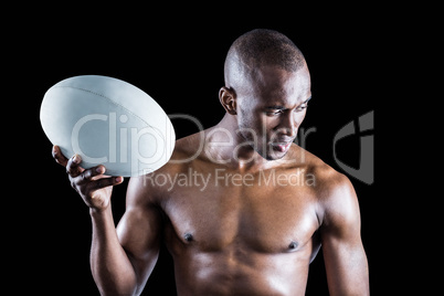 Concentrated shirtless sportsman holding rugby ball