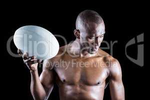 Concentrated shirtless sportsman holding rugby ball