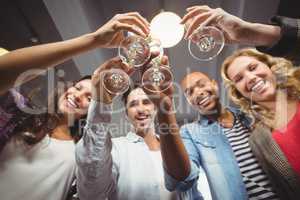 Low angle portrait of cheerful colleagues toasting in office