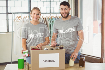 Portrait of smiling volunteers separating donations stuffs