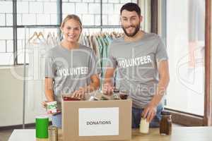 Portrait of smiling volunteers separating donations stuffs