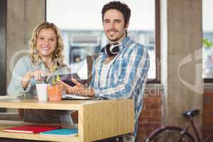 Happy business people holding digital tablet by table in office