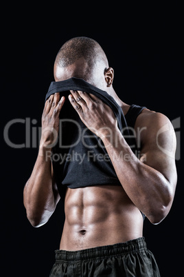 Muscular man wiping sweat with tank top
