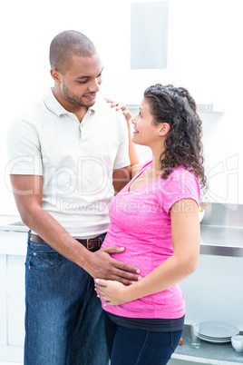 Husband touching pregnant wife belly while looking at each other