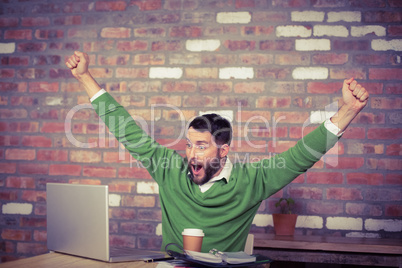 Happy businessman cheering while looking at laptop