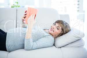 Portrait of happy woman reading book at home