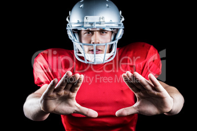 Portrait of sportsman defending while playing American football