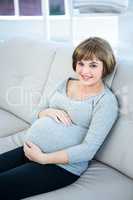 High angle view of smiling pregnant woman sitting at home
