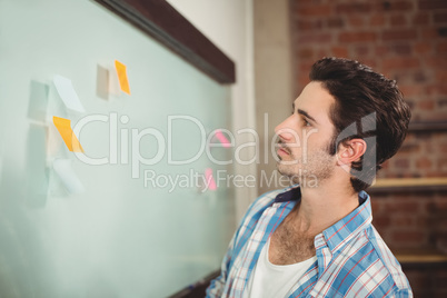 Businessman reading sticky notes on glass board