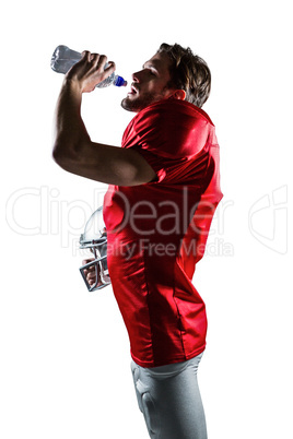 American football player in red jersey holding helmet while drin