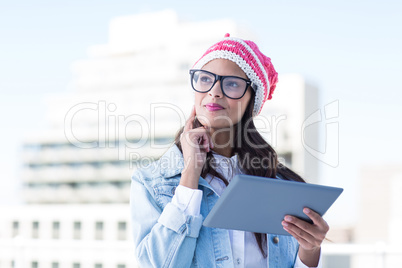 Thoughtful woman holding tablet pc with finger on cheek