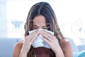 Sick woman sneezing in tissue