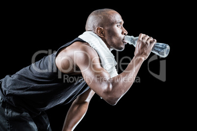 Side view of muscular man drinking water while bending