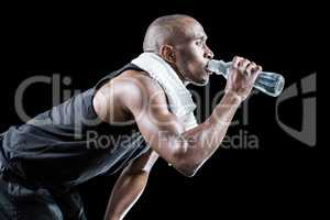 Side view of muscular man drinking water while bending