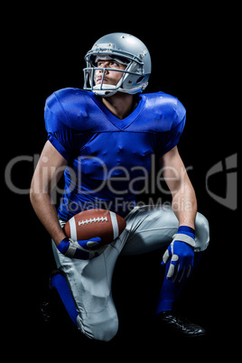 American football player with ball kneeling