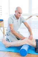 Trainer working with man on exercise mat