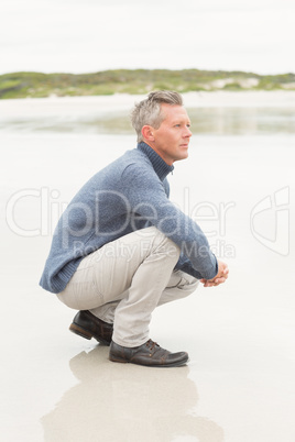 Man crouched down at the shore