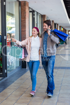 Smiling couple walking hand in hand and going window shopping