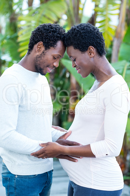 Man touching pregnant wife belly while standing