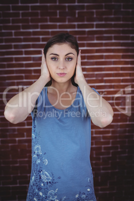 Pretty brunette with hands over ears