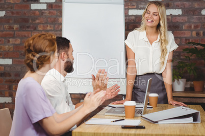 Colleagues applauding businesswoman in office