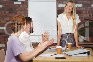 Colleagues applauding businesswoman in office