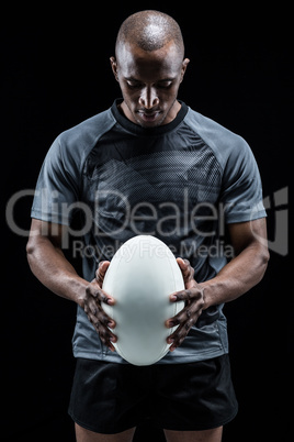 Thoughtful athlete looking at rugby ball