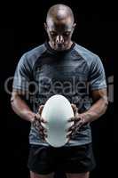 Thoughtful athlete looking at rugby ball