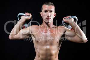 Confident shirtless athlete holding kettlebells
