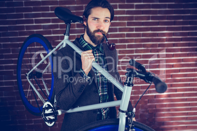 Portrait of smart confident man with bicycle smoking pipe