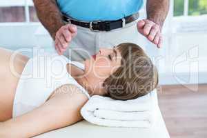 Pregnant woman resting while male therapist performing reiki