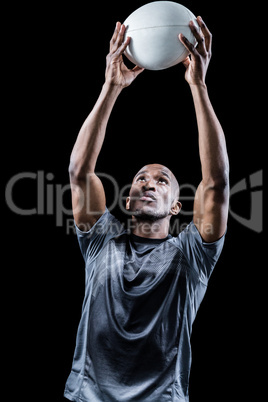 Sportsman looking up while catching rugby ball