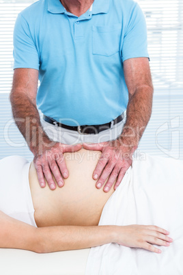 Male masseur massaging belly of pregnant woman