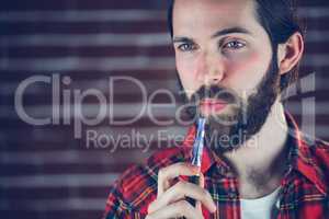 Hipster with electronic cigarette looking away
