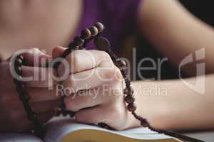 Woman praying with her bible and rosary beads