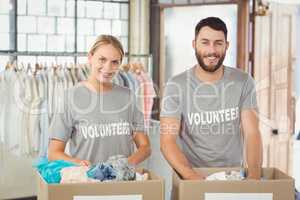 Portrait of smiling volunteers separating donations clothes