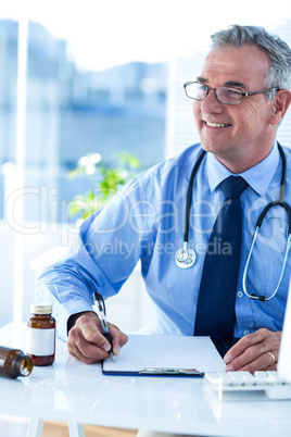 Smiling male doctor looking away in clinic