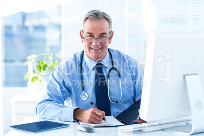 Portrait of smiling male doctor with document in hospital