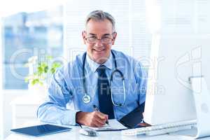 Portrait of smiling male doctor with document in hospital